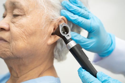 Otolaryngologist ENT physician doctor examining senior patient ear otoscope hearing loss photo