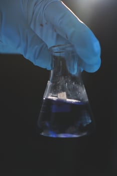 A hand holding a beaker filled with blue liquid photo
