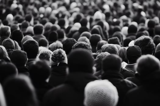Crowds gather in anticipation at a large outdoor event on a cool evening, creating a sea of diverse expressions and energy photo