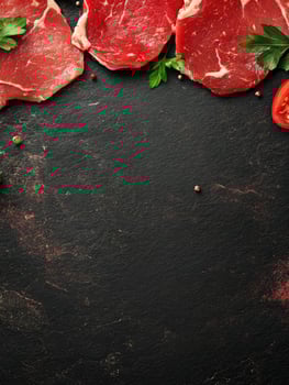 Fresh Raw Beef Steaks with Herbs on Dark Stone Background photo