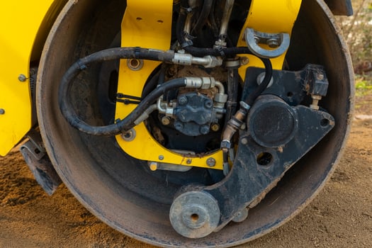 Detailed close-up of a yellow road roller's hydraulic system in action on a construction site photo