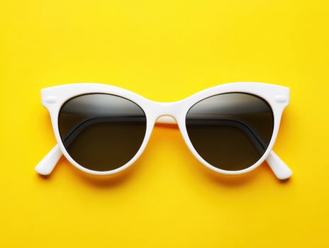 Stylish white sunglasses against a bright yellow background photo