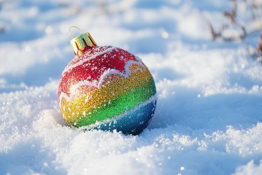 Colorful Christmas Ornament Resting in Fresh White Snow in Winter Sunlight photo