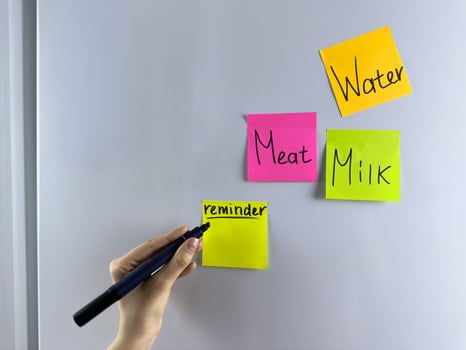 Hand writing note on colored reminder hanging on refrigerator photo