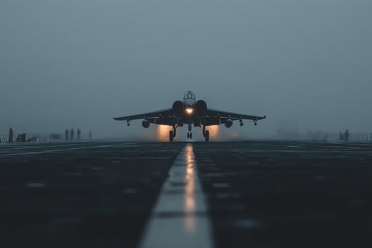 Military jet embarks on powerful ascent from aircraft carrier amidst foggy dawn haze photo