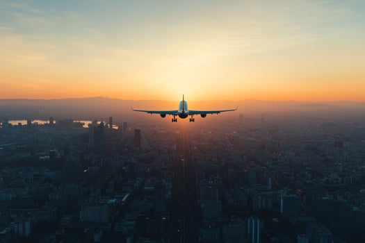 Plane ascends into a vibrant sky as the sun sets over the cityscape, painting a beautiful horizon with warm colors photo