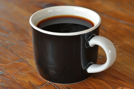 A black mug filled with rich dark coffee on a table photo