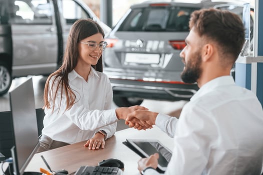 Sitting by table and working. Man with woman ,in white clothes are in the car dealership together photo