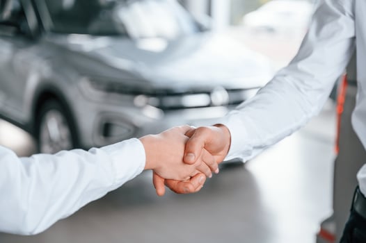 Close up view of handshake.. Man with woman in white clothes are in the car dealership together photo