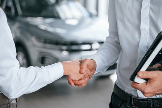 Close up view of handshake. Man with woman in white clothes are in the car dealership together photo
