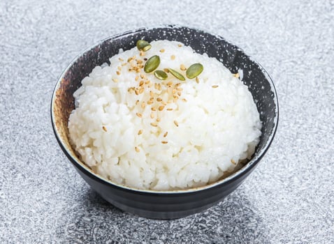 Fragrant rice or Steamed White Rice topped Sesame Seeds, and Pumpkin Seeds, served in black bowl isolated stone background side view of Kong Asian street food photo