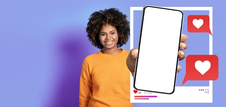 An influencer smiles while holding a smartphone in front of a vibrant background. The screen displays a mockup of social media interactions, highlighting likes and messages. photo
