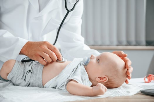 Close ,up ,view. Using stethoscope. Doctor in white coat is taking care of little toddler indoors photo