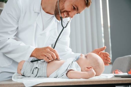 Close ,up view. Using stethoscope. Doctor in white coat is taking care of little toddler indoors photo