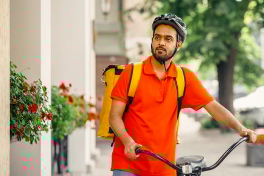 Eco transport and active lifestyle, mobile work in city. Serious millennial indian male courier in uniform and safety helmet, with big backpack and bicycle looking for clients address for delivery photo