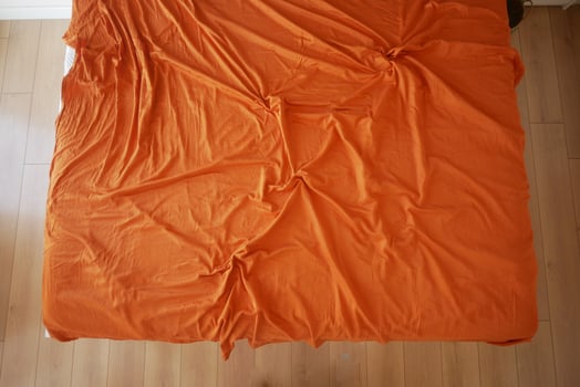 Bright orange bedspread on a wooden floor in a cozy room photo