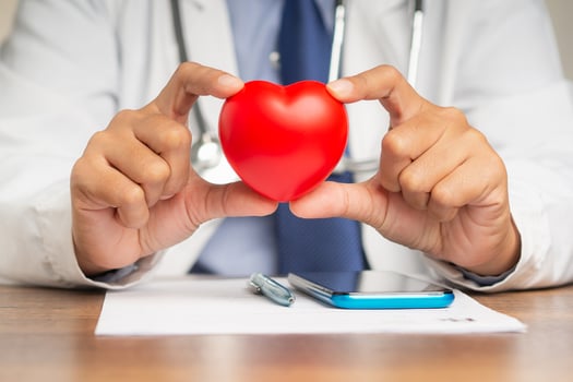 Doctor hands holding a red heart shape symbol while sitting in the hospital or clinic photo