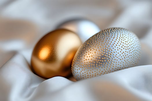 Golden and silver easter eggs resting on white silk fabric photo