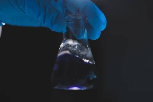 A person holding a test tube with purple liquid photo