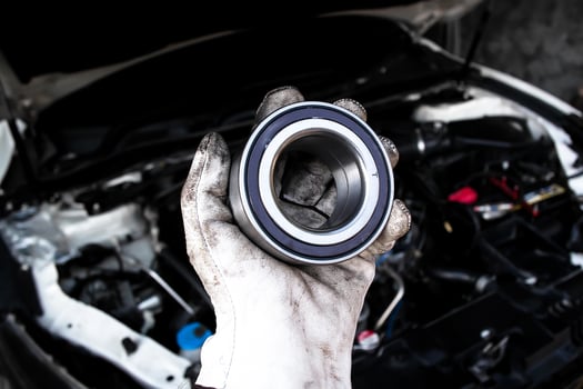 Close up of mechanic holding ABS bearing of front car wheel over car engine , Automotive parts concept photo