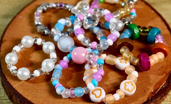 Cute colorful beads ring with various designs isolated on horizontal wooden coaster background. photo