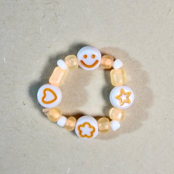 Cute small orange and white colored ring beads accesories isolated on square paper surface background. photo