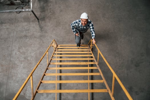 View from the, top of ladder. Factory male worker in uniform is indoors photo