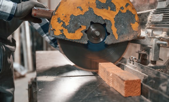 Cutting the ,wood ,by saw. Factory male worker in uniform is indoors photo