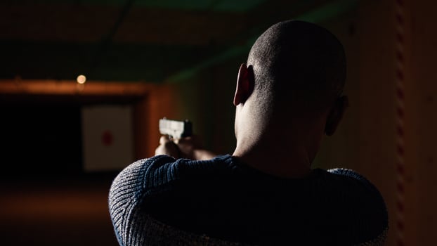 Shooting gallery customer using pistol to hit paper targets with ammo. Close up shot of man at professional firing range, shooting bullseyes, enjoying using weapons, camera A photo
