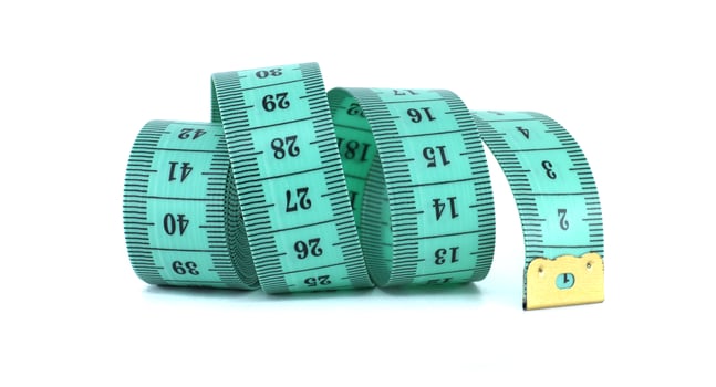 A light green measuring tape curled on a white background, a common tool for sewing projects. photo