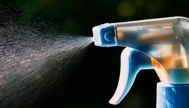 Spray Bottle Releasing a Fine Mist of Liquid in a Vibrant Outdoor Setting During the Day photo