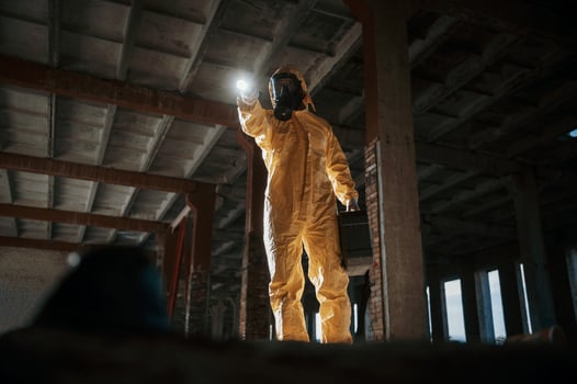 Using the flashlight... Man dressed in chemical protection suit in the ruins of the post apocalyptic building photo