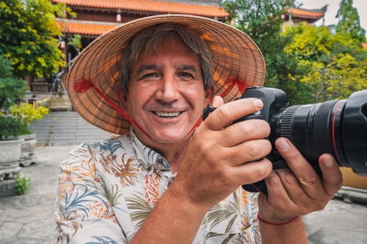 happy elderly man travel photographer in Vietnamese hat takes pictures with camera at a pagoda in Nha Trang in Vietnam. Tourism and travel in Asia photo