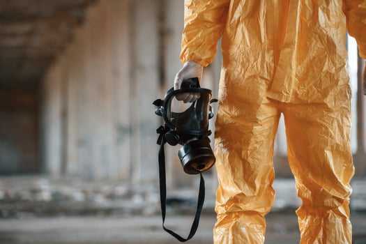 Holding gas, mask. Man dressed in chemical protection suit in the ruins of the post apocalyptic building photo