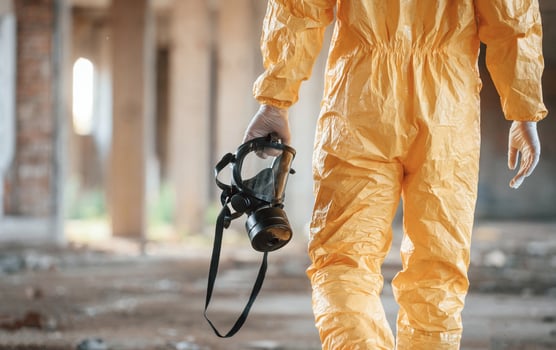 Respirator in hand.. Man dressed in chemical protection suit in the ruins of the post apocalyptic building photo