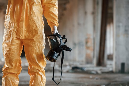 Holding gas mask. Man ,dressed in chemical protection suit in the ruins of the post apocalyptic building photo