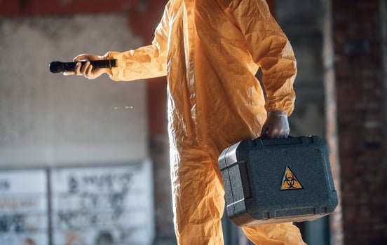 Holding case ,and flashlight. Man dressed in chemical protection suit in the ruins of the post apocalyptic building photo