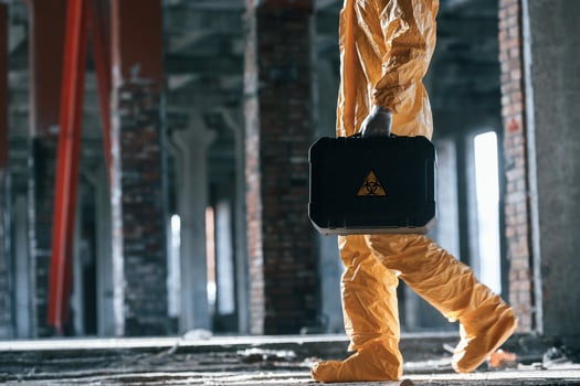 The case ,with, biohazard sign on it. Man ,dressed in chemical protection suit in the ruins of the post apocalyptic building photo
