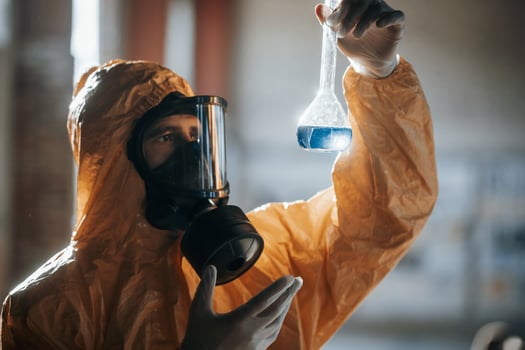 Examining ,radioactive liquid. Man dressed in chemical protection suit in the ruins of the post apocalyptic building photo