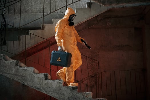 On ,stairs with flashlight and case. Man dressed in chemical protection suit in the ruins of the post apocalyptic building photo