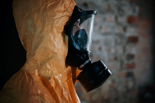 Side view. Man dressed in chemical protection suit in the ruins of the post apocalyptic building photo
