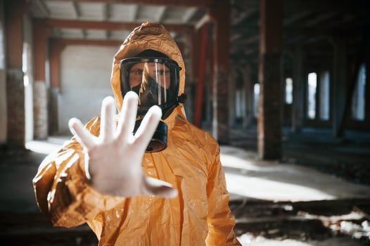 Stop sign by hand. Man dressed in chemical ,,protection suit in the ruins of the post apocalyptic building photo