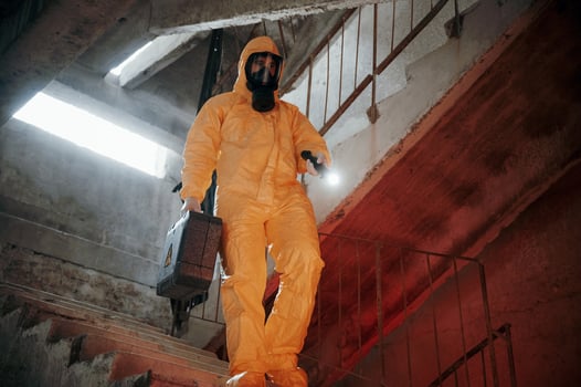 On ,the stairs. Man dressed in chemical protection suit in the ruins of the post apocalyptic building photo