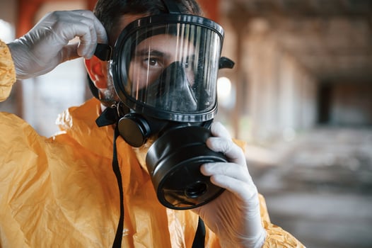 Wearing the respirator.. Man dressed in chemical protection suit in the ruins of the post apocalyptic building photo