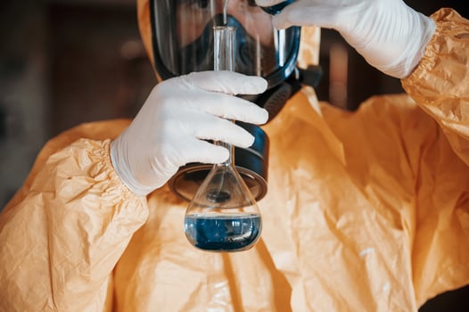 Holding a test tube and examining radioactive liquid. Man dressed in chemical protection suit in the ruins of the post apocalyptic building photo