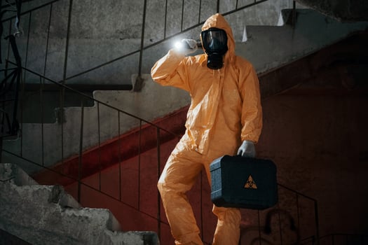 On ,stairs with flashlight and case. .Man dressed in chemical protection suit in the ruins of the post apocalyptic building photo