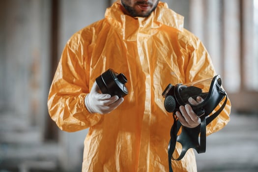 Holding a respirator. Man dressed in chemical protectio..n suit in the ruins of the post apocalyptic building photo