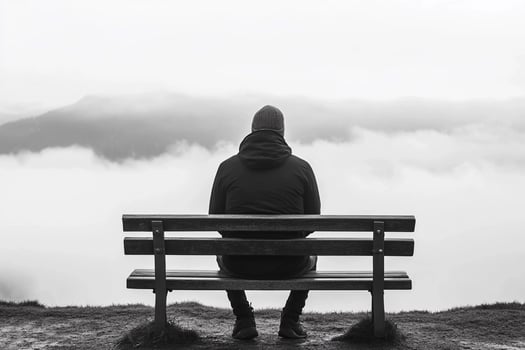 Man sitting on bench looking out over the clouds photo