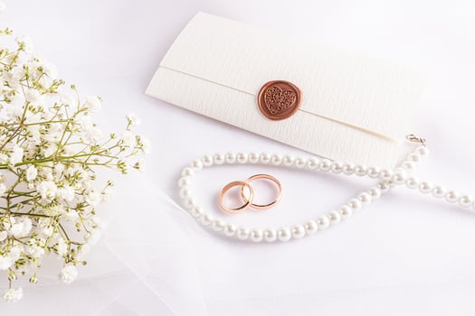 A layout, a sample of a wedding card or invitation in a classic white tone with gypsophila flowers, pearl beads, rings, an envelope. photo