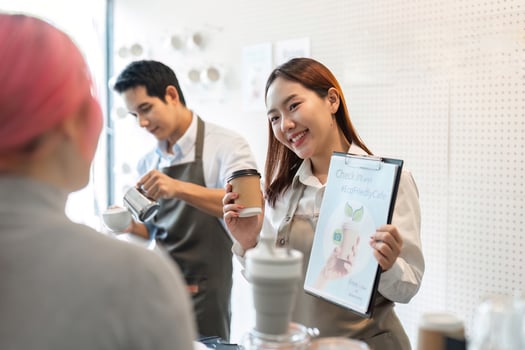 Sustainable Practices and Friendly Service. A barista showcases eco-friendly initiatives while serving coffee. photo
